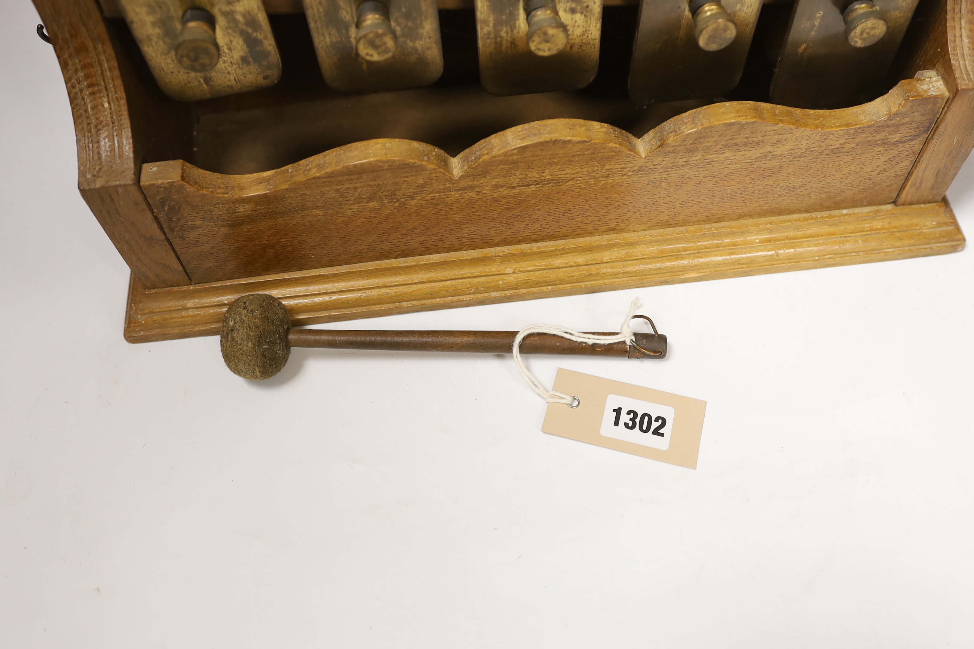 An early 20th century oak wall mounting five note glockenspiel with resonators for each bar, playing a major arpeggio starting on the tonic, with beater, 65cm high, 42cm wide, 13cm deep